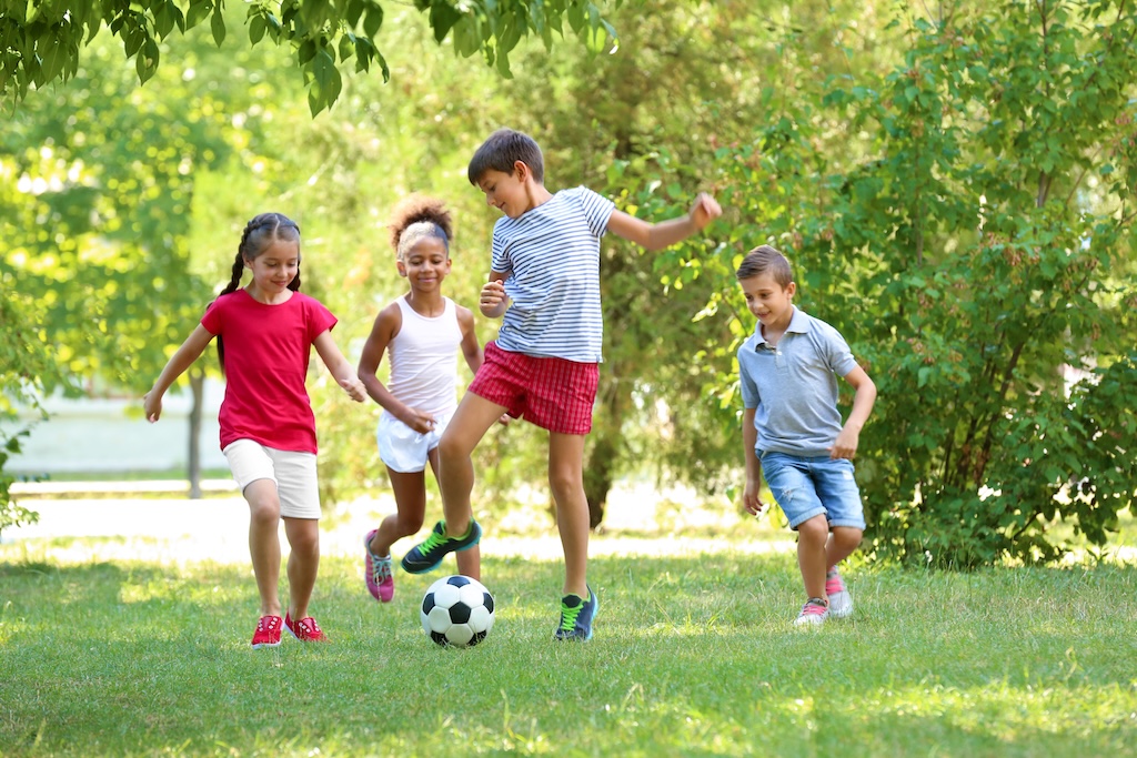 Cute children playing football in park